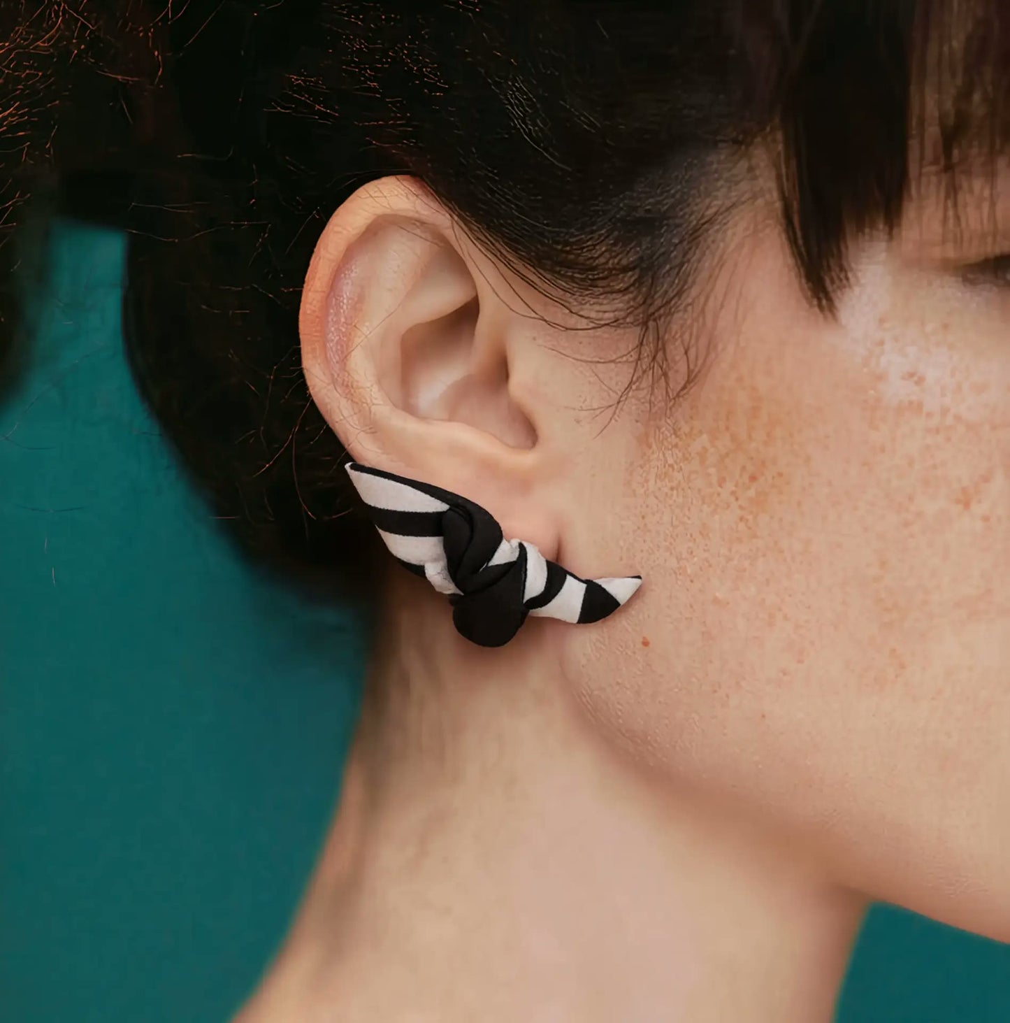 Close up of Papillon silk knot earring on ear